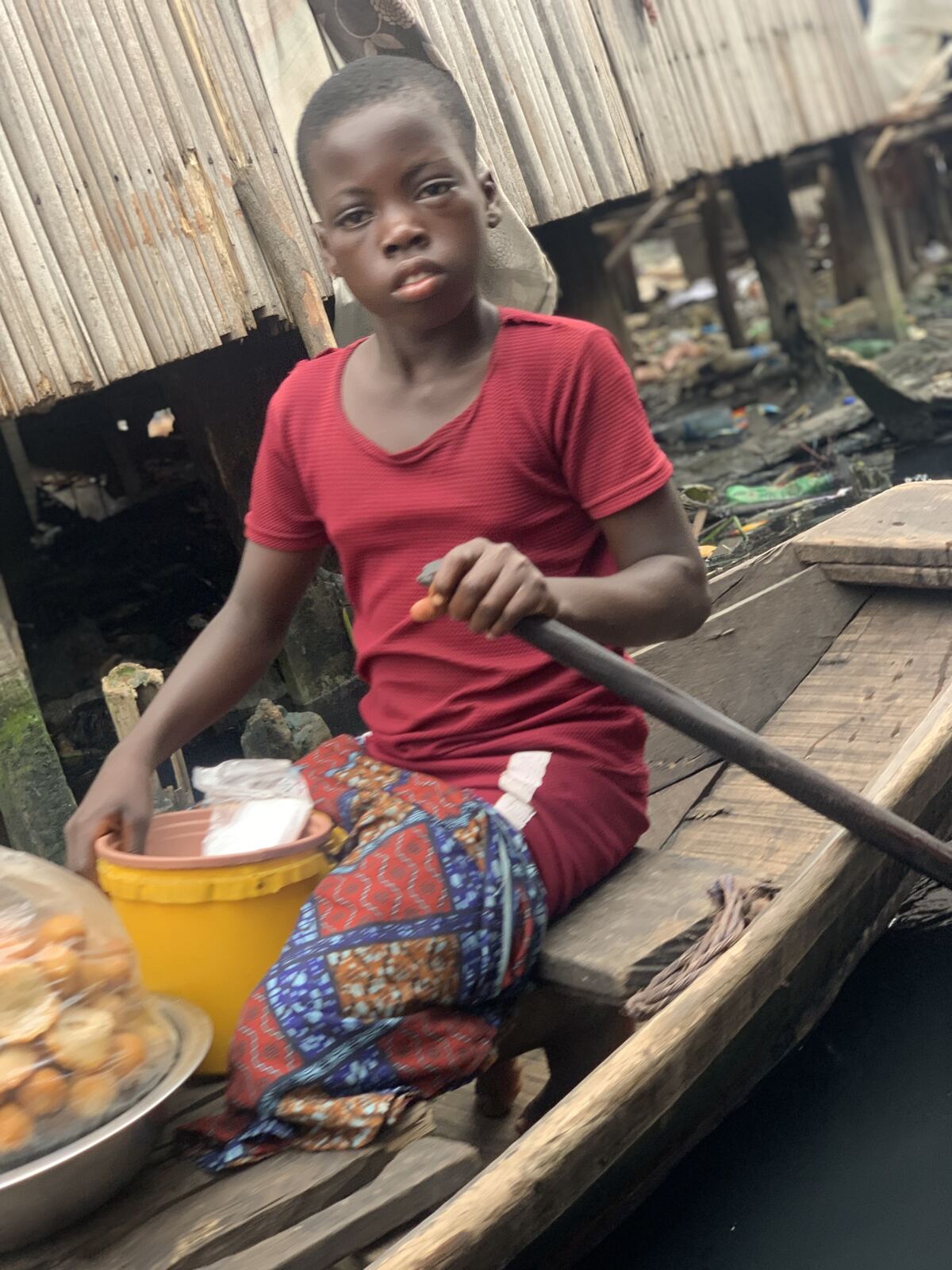 A girl paddling a canoe with a bowl of food beside her