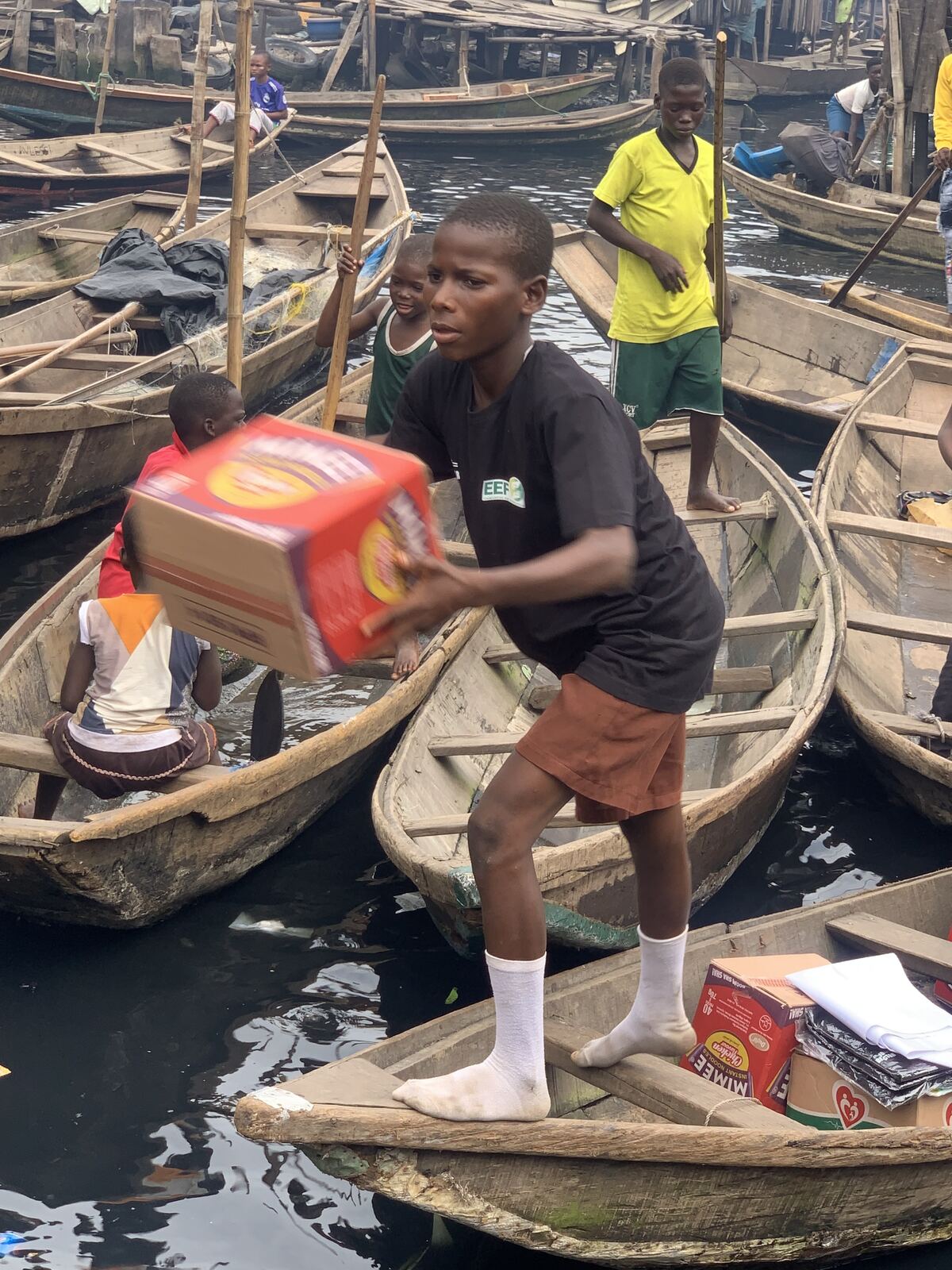 A volunteer stepping between canoes with a box of food